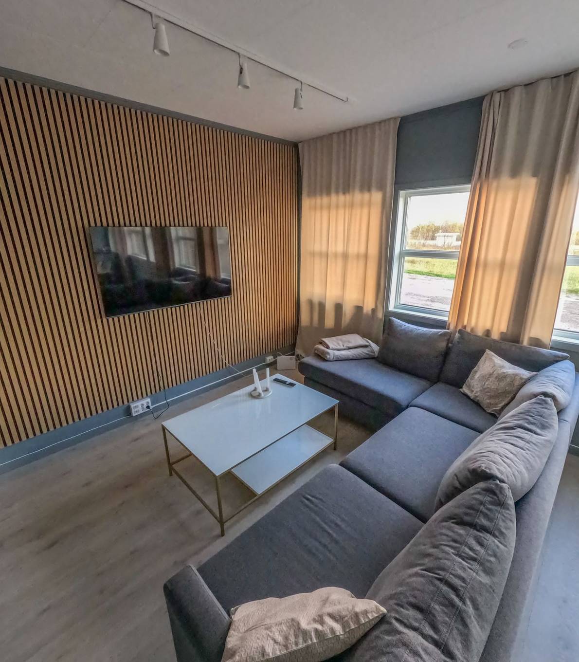 Stue i Suite 6 med spilevegg og grå hjørnesofa