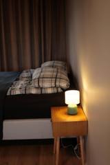 Seng med rutete sengetøy og nattbordlampe i Suite 3
